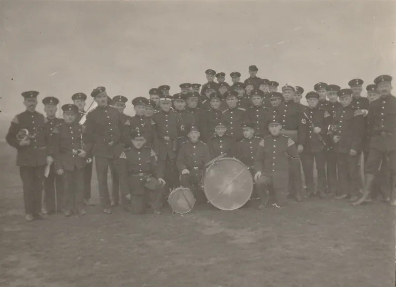 Schwarz-Weiß-Gruppenfoto: die Feuerwehrkapelle in Uniform mit großer Trommel und Blasinstrumenten