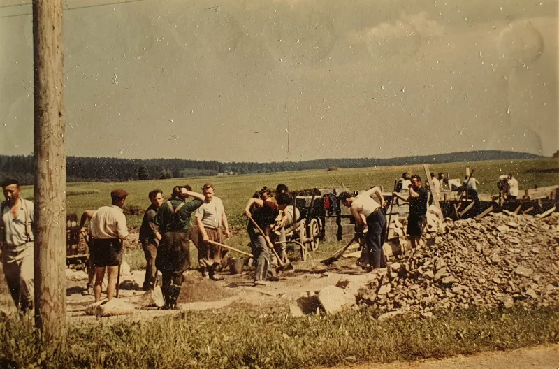 Farbfoto: Männer mit Spaten und Schaufeln beim Ausschachten, daneben ein Steinhaufen