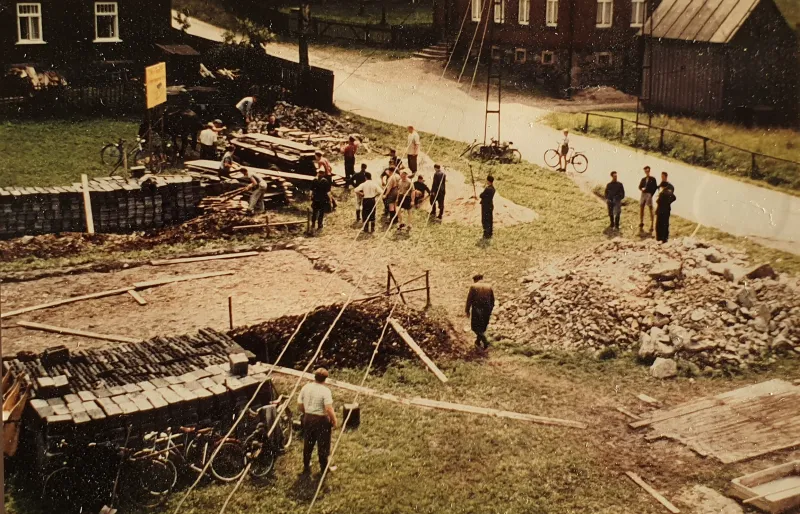Farbfoto: Baustelle mit Steinstapeln, Holz und abgestellten Fahrrädern der Helfer