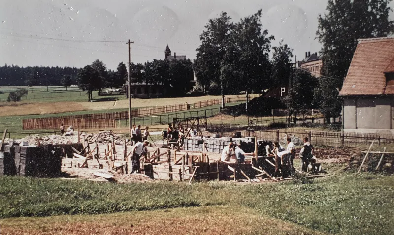 Farbfoto: Blick über die Baustelle, im Hintergrund Bäume und ein Kirchturm