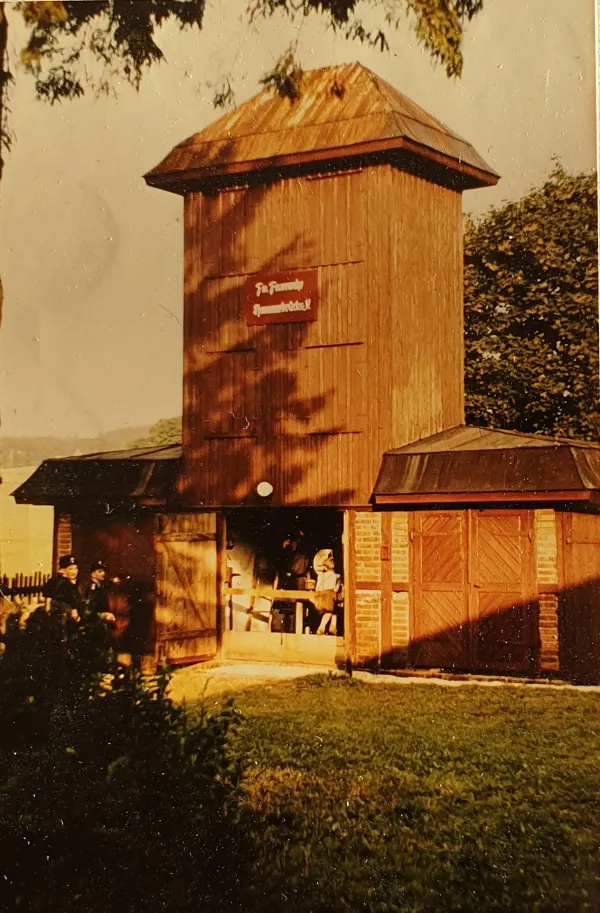 Farbfoto: das hölzerne Spritzenhaus mit Schlauchturm und Schild der Feuerwehr Hammerbrücke