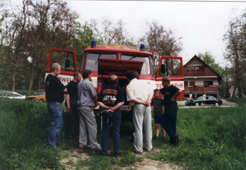 Farbfoto: Kameraden stehen vor dem Robur LO mit geöffneter Motorhaube auf einer Wiese in Harta